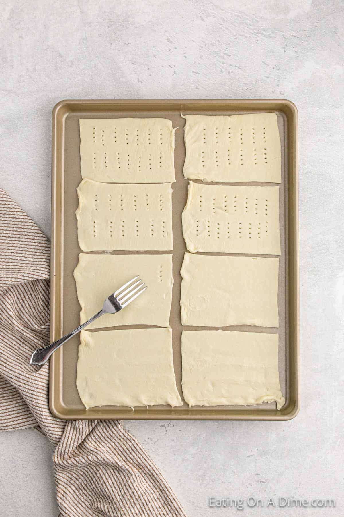Poking holes into the 8 puff pastry sheets on a baking sheet with a fork