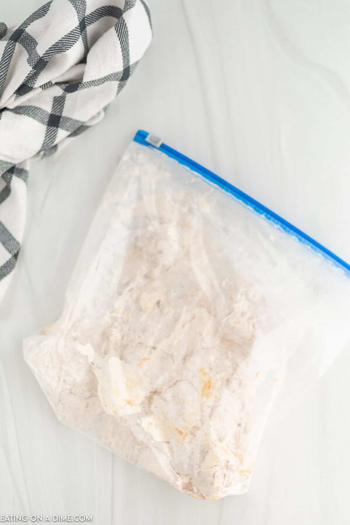 Zip lock bag with flour mixture with chicken coated with flour