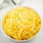 Spaghetti squash in a white bowl topped with parmesan cheese.