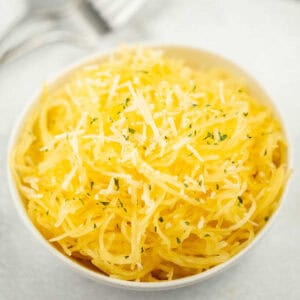 Spaghetti squash in a white bowl topped with parmesan cheese.