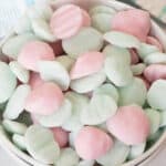 A bowl filled with pastel pink and pale green Frozen Yogurt Bites, shaped into small, round discs with ridged tops.