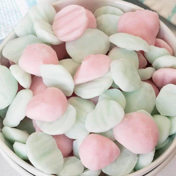 A bowl filled with pastel pink and pale green Frozen Yogurt Bites, shaped into small, round discs with ridged tops.