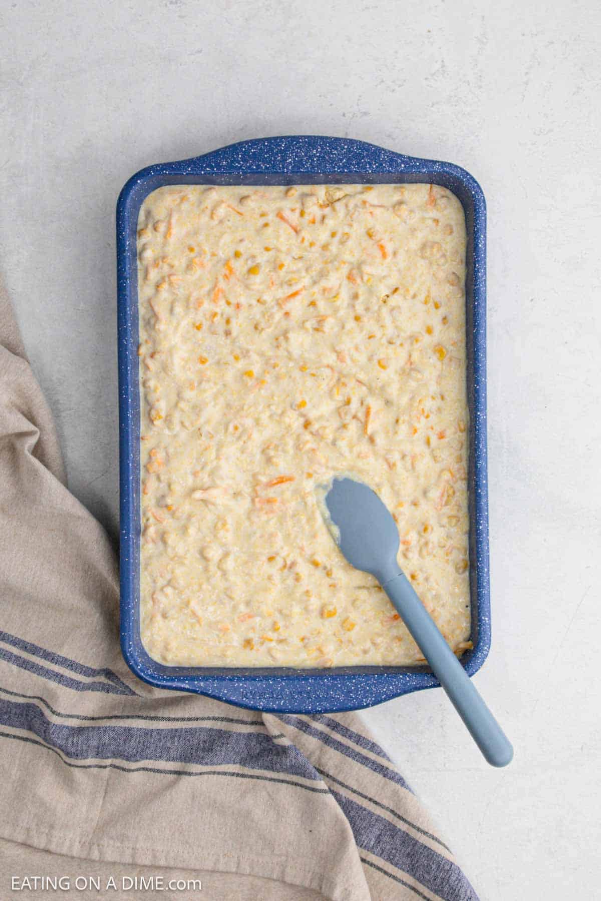 Spreading the cornbread mixture in a baking dish with a spatula.