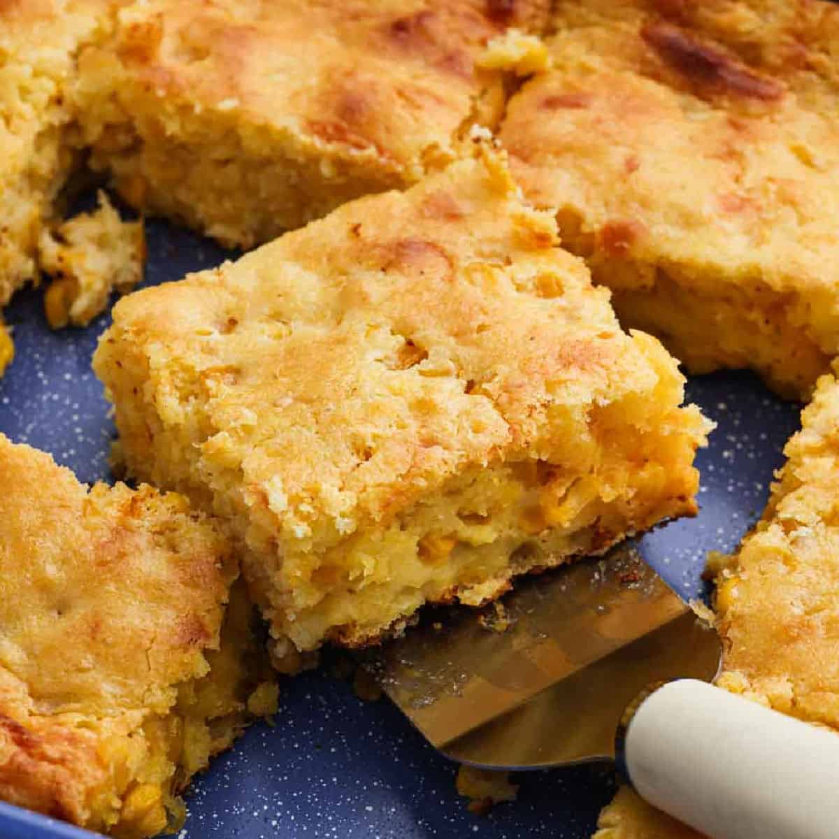 Cornbread Casserole in a baking dish and one slice ready to serve on a spatula.