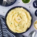 Mashed potatoes in a bowl with butter and parsley.
