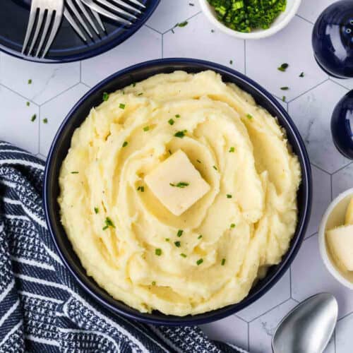 Mashed potatoes in a bowl with butter and parsley.