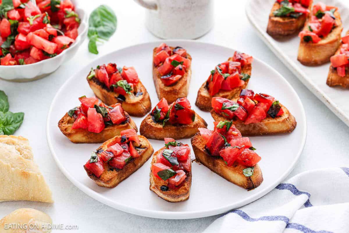 Plate of bruschetta topped with diced tomatoes and basil on toasted bread slices, arranged in a circle.