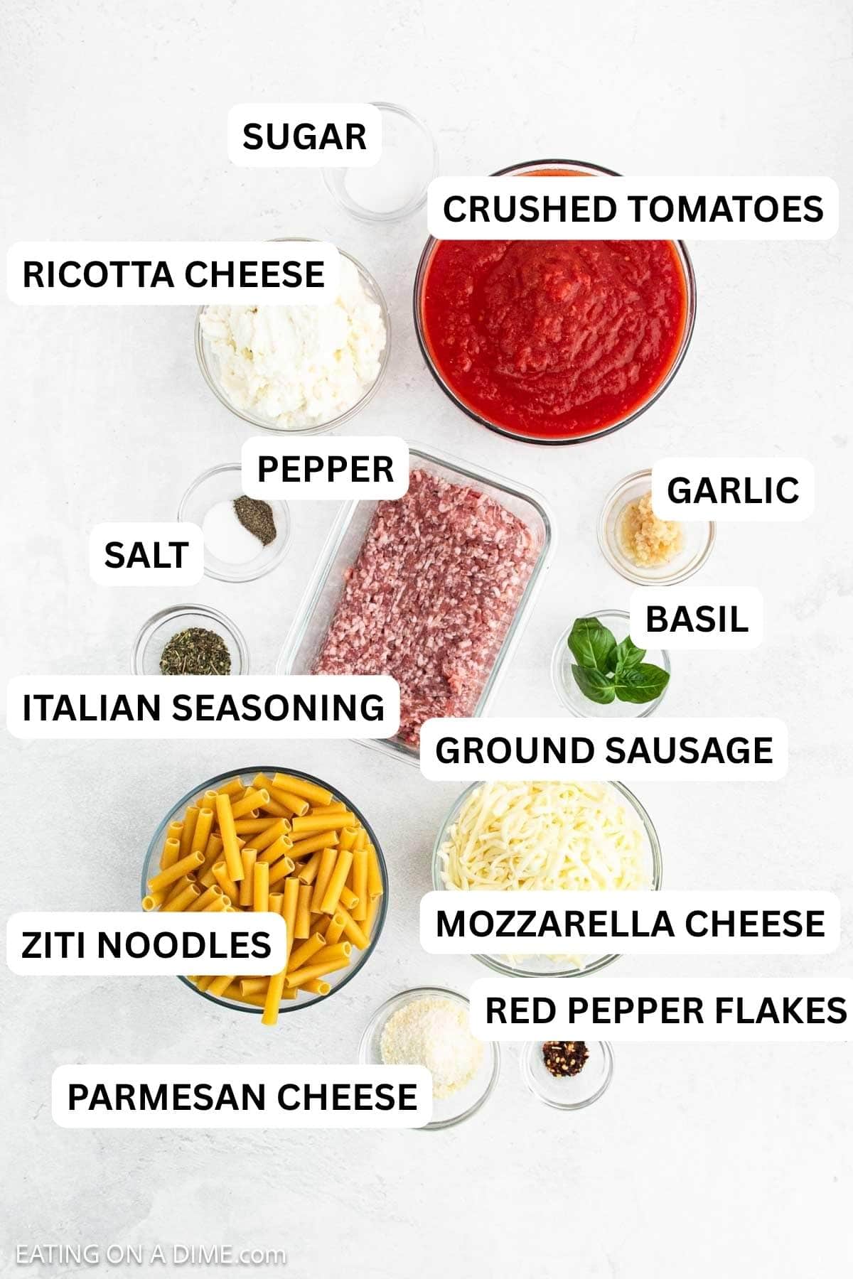 Ingredients needed for this recipe which includes Ground Sausage, garlic, Italian Seasoning, Crushed Tomatoes, salt, sugar, red pepper flakes, pepper, ziti pasta, ricotta cheese, mozzarella cheese, parmesan cheese, and basil.