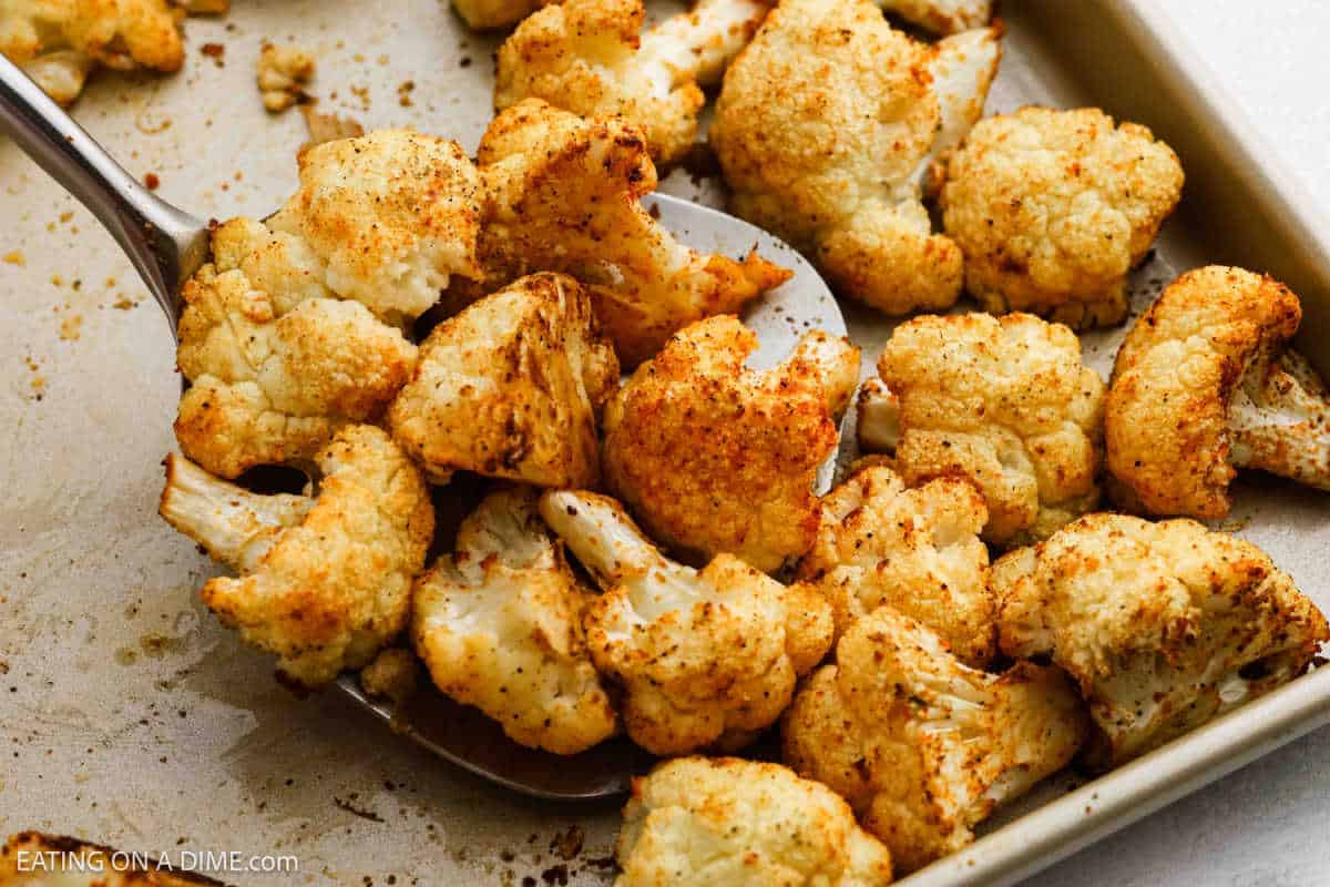 Roasted Cauliflower on a baking sheet with a spatula scooping up a serving.
