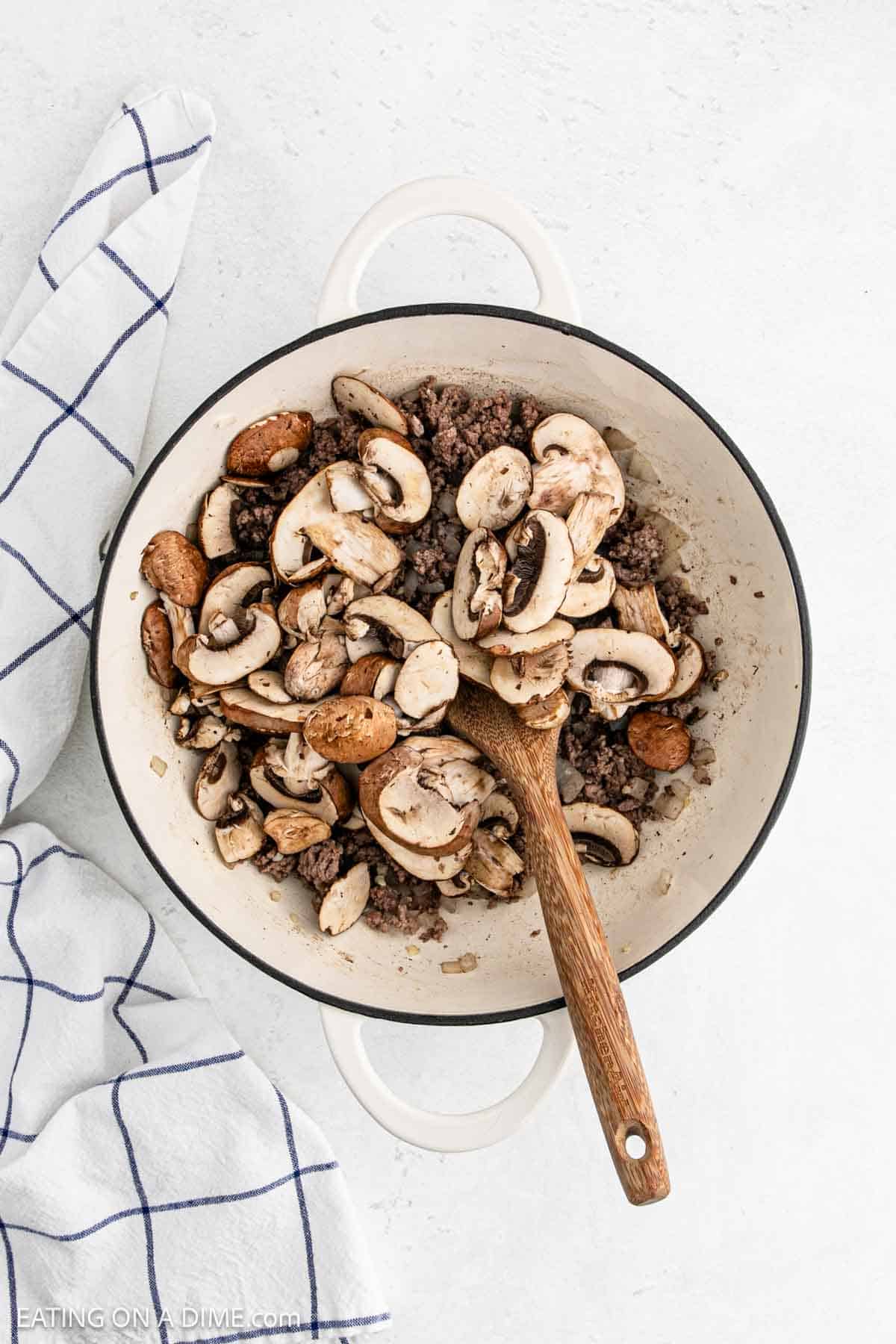 Adding slice mushrooms in a large pot with ground beef mixture