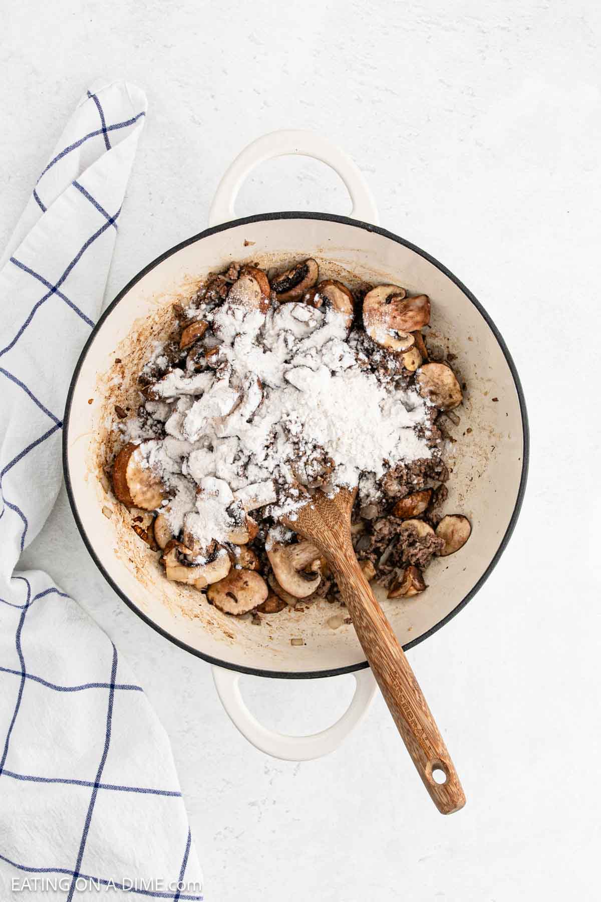 Flour added to large pot with slice mushrooms and ground beef