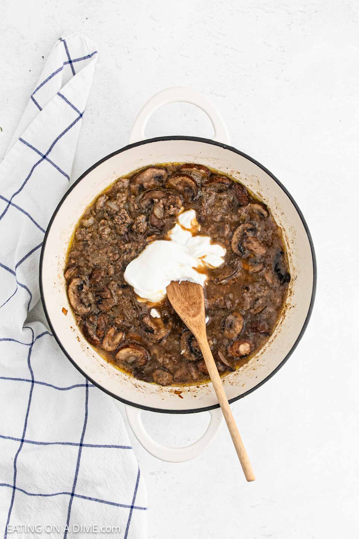 Sour cream added to large pot with ground beef mixture with slice mushrooms