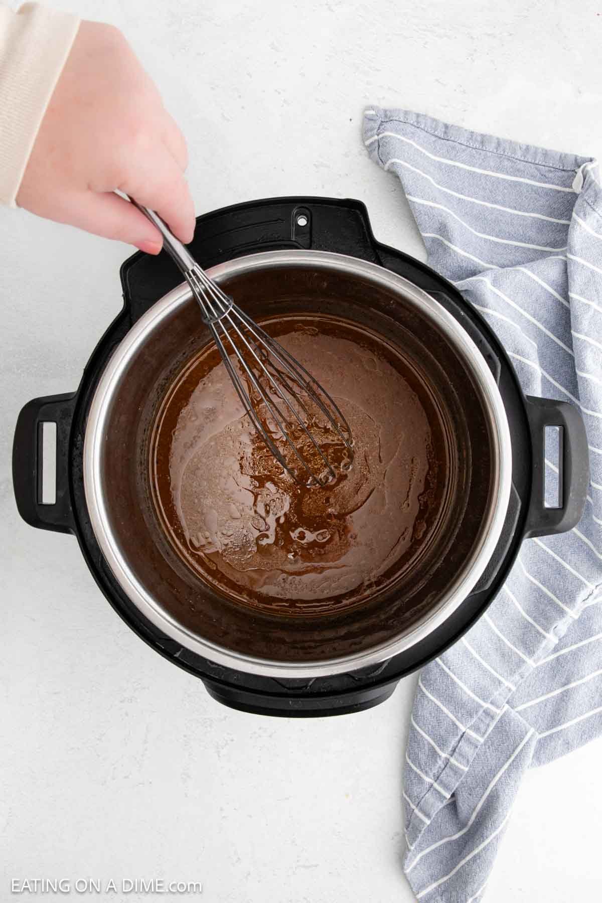 Whisking chicken broth with the chicken thigh juices in the instant pot