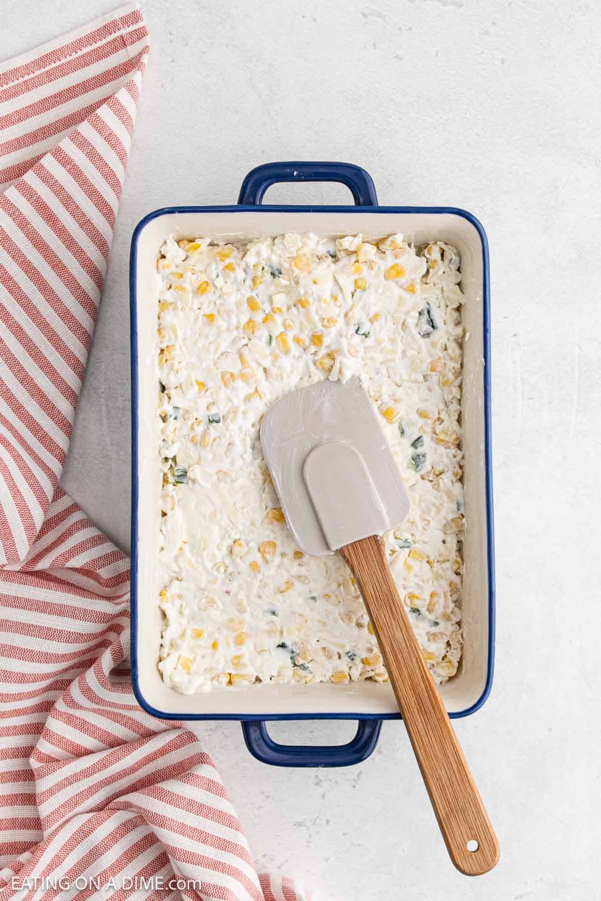 Spreading the corn dip in the baking dish with a spatula 