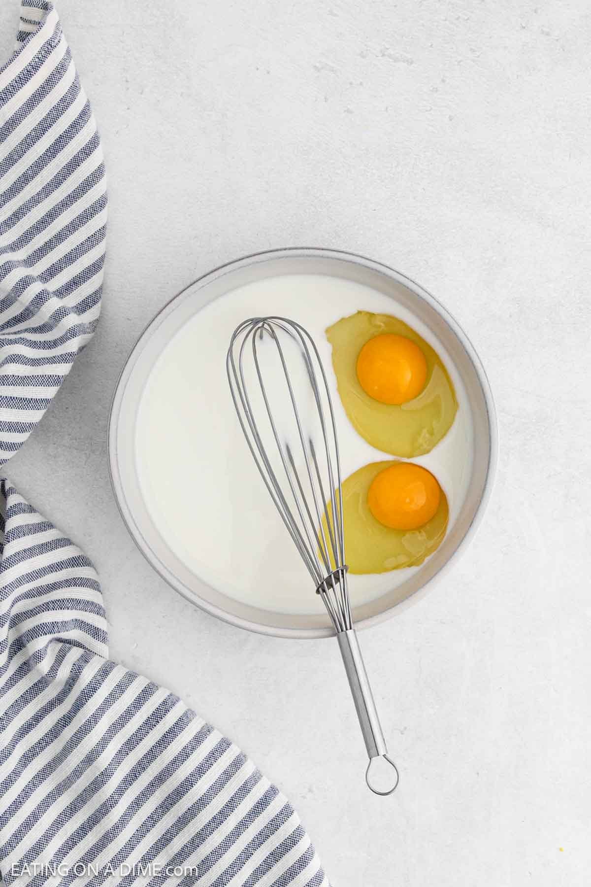 Milk and eggs whisk together in a bowl