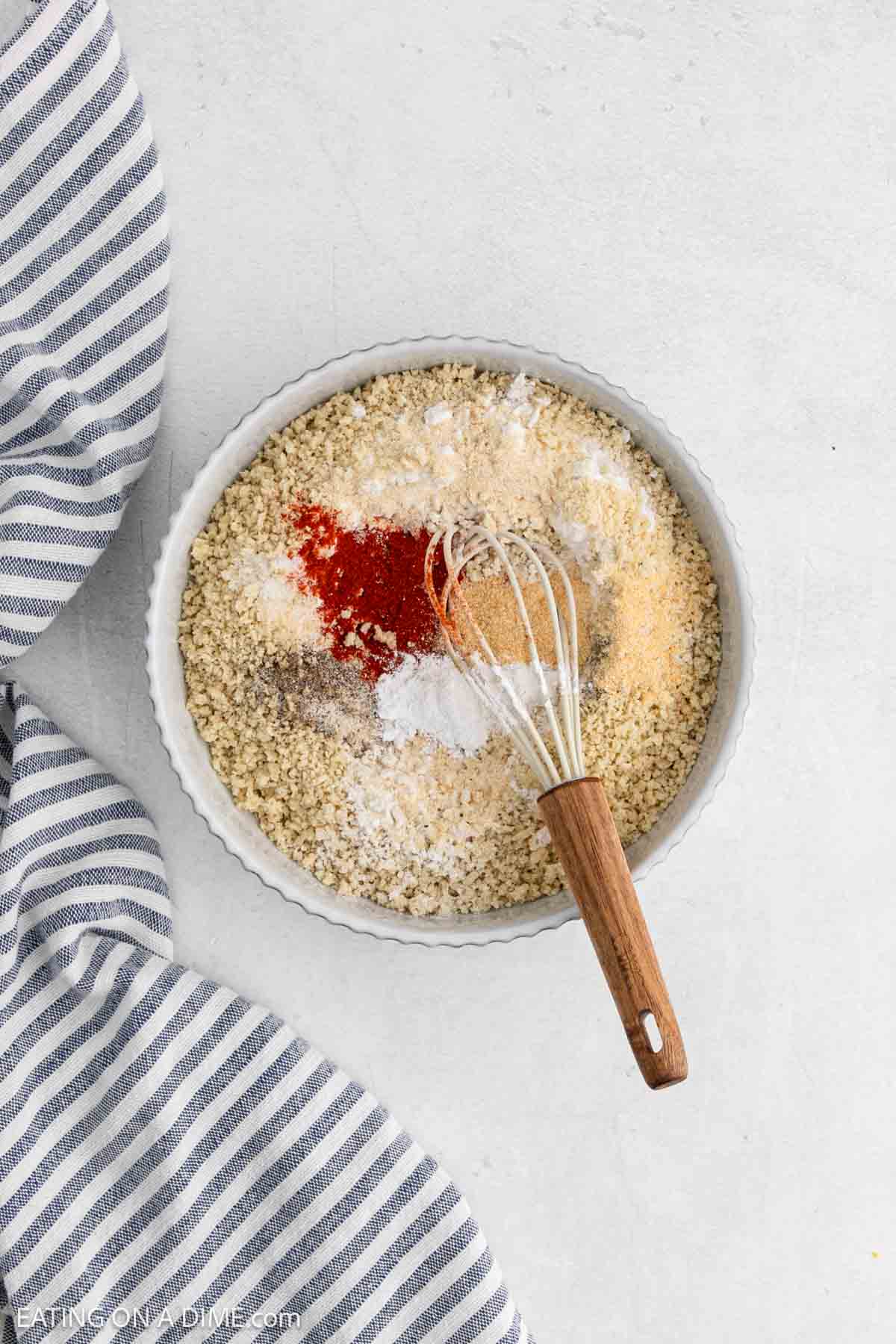 Seasoning and bread crumbs in a bowl with a whisk