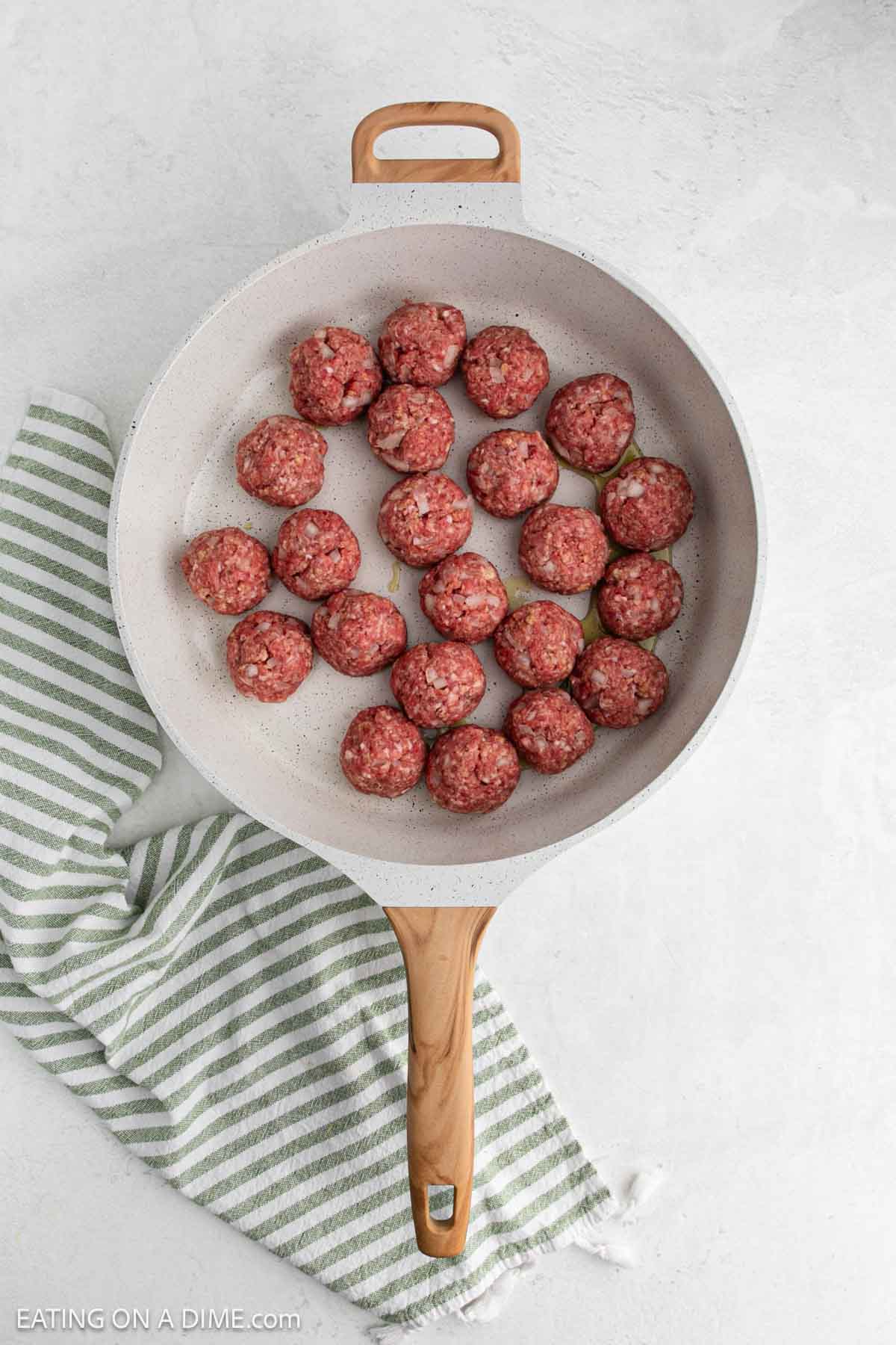 Uncooked meatballs in a skillet