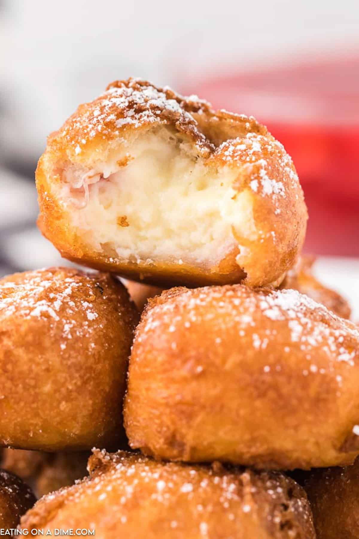 Fried Cheesecake stacked on a platter topped with powdered sugar