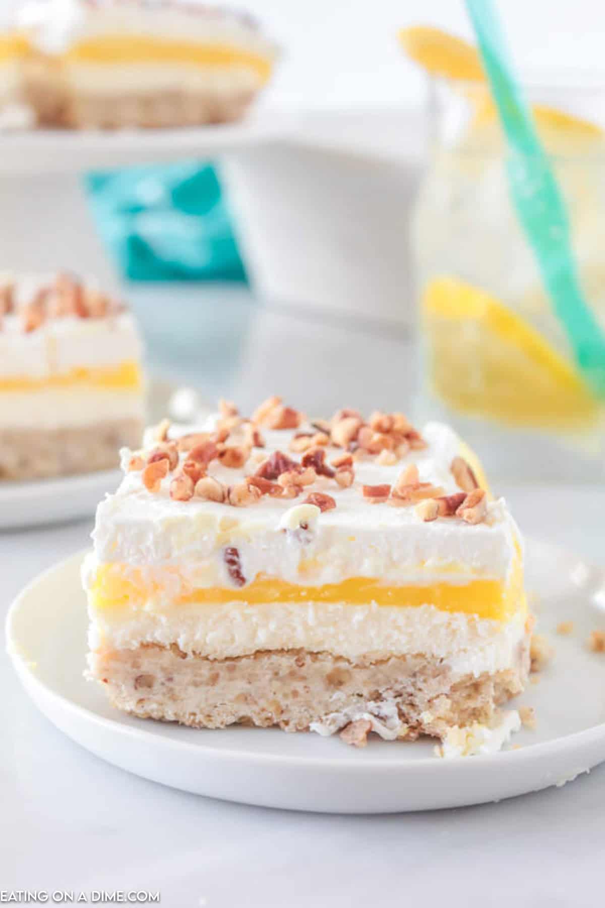 A slice of lemon lush dessert on a plate topped with chopped nuts