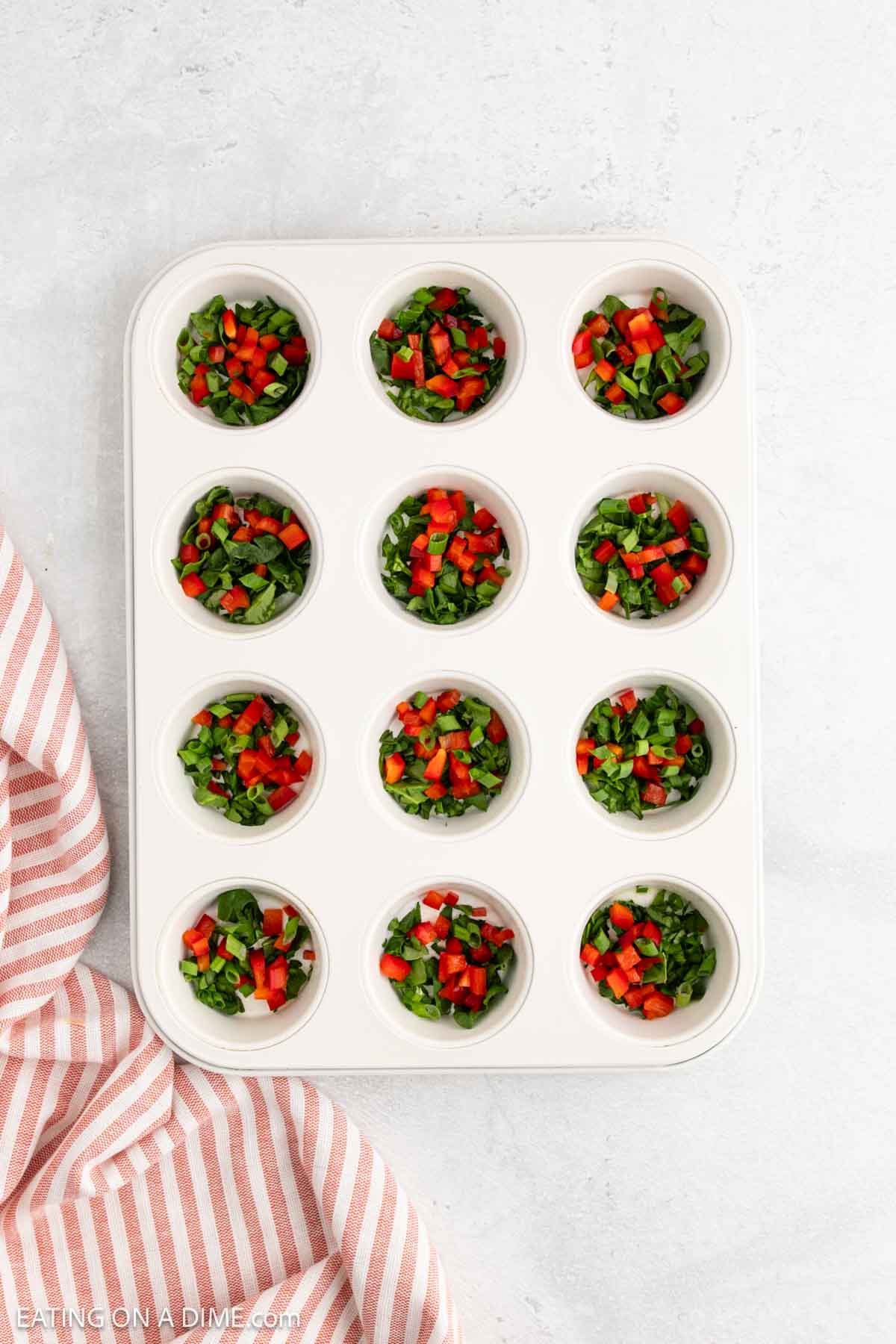 Diced vegetables placed in the muffin cups of a muffin pan
