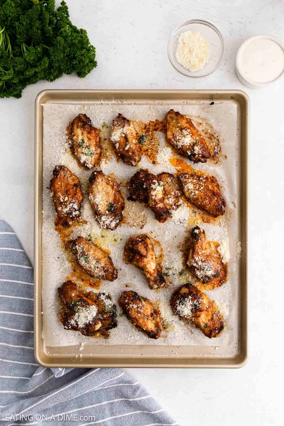 Seasoned cooked chicken wings on a baking sheet lined with parchment paper