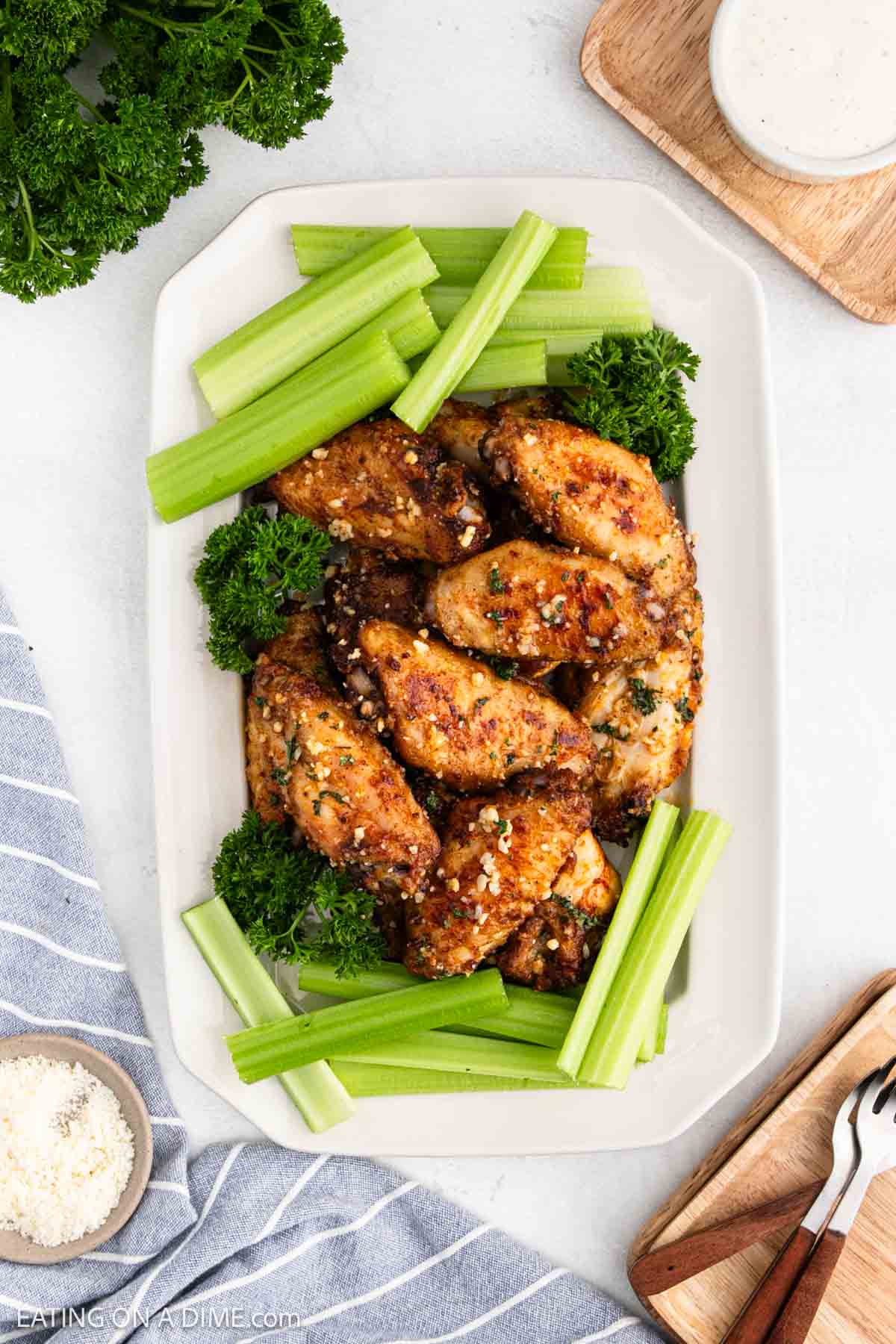 Garlic Parmesan Chicken Wings stacked on a white platter with fresh celery sticks
