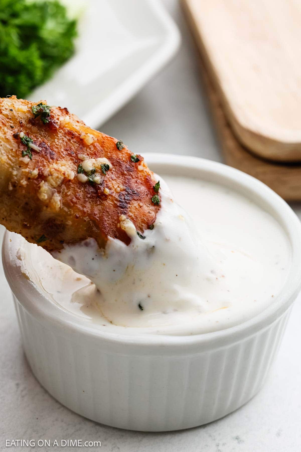 Dipping the cooked chicken wings in a bowl of rach