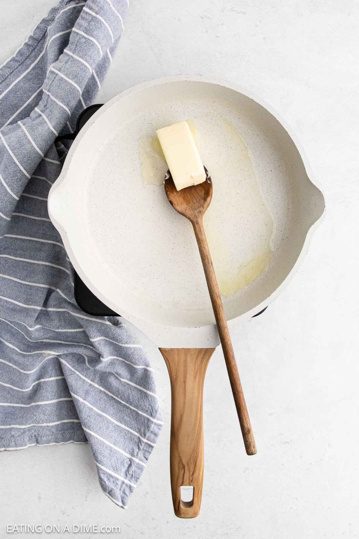 Melting butter in a large skillet with a wooden spoon