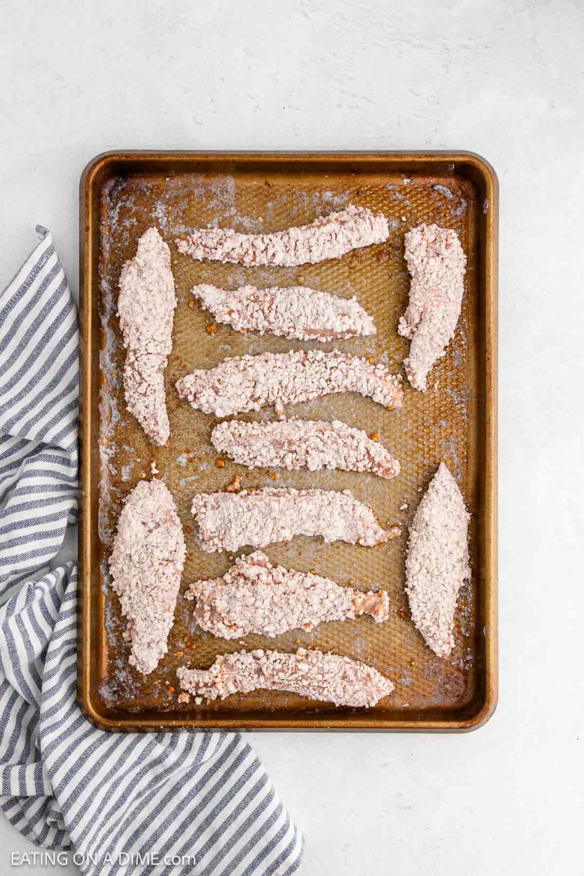 Breaded chicken tenders on a baking sheet