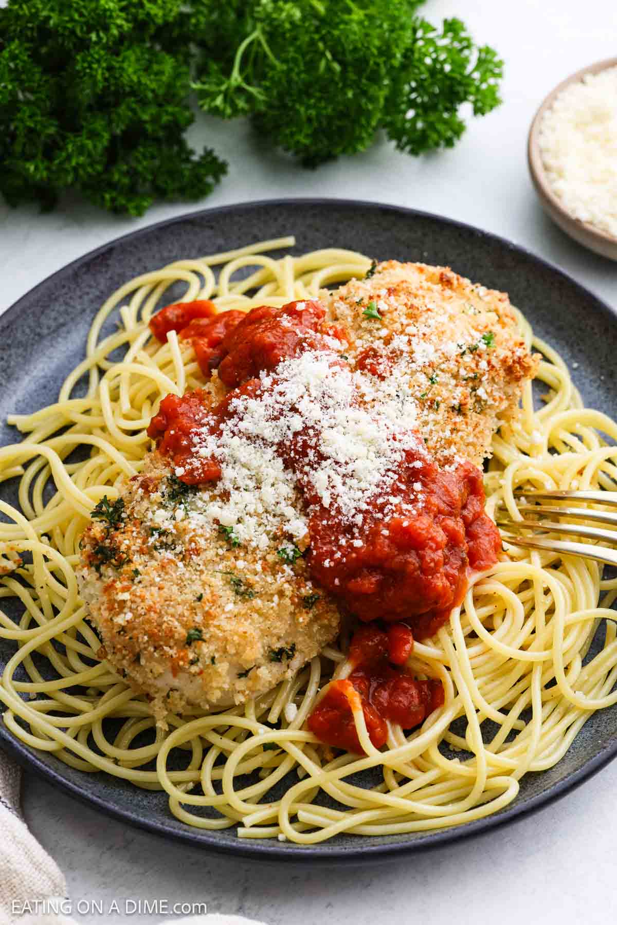Parmesan Crusted Chicken Breast on a plate with spaghetti noodles topped with sauce