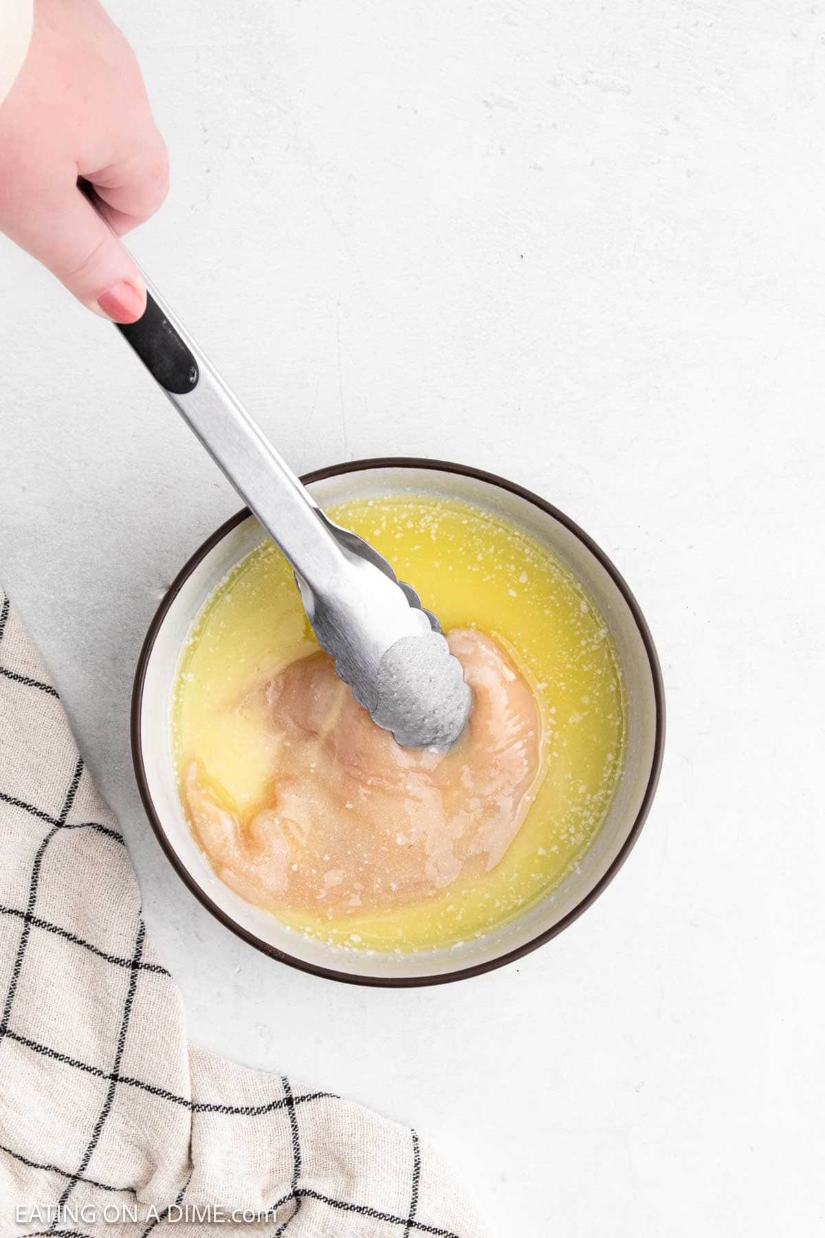 Dipping the chicken into the melted butter with tongs