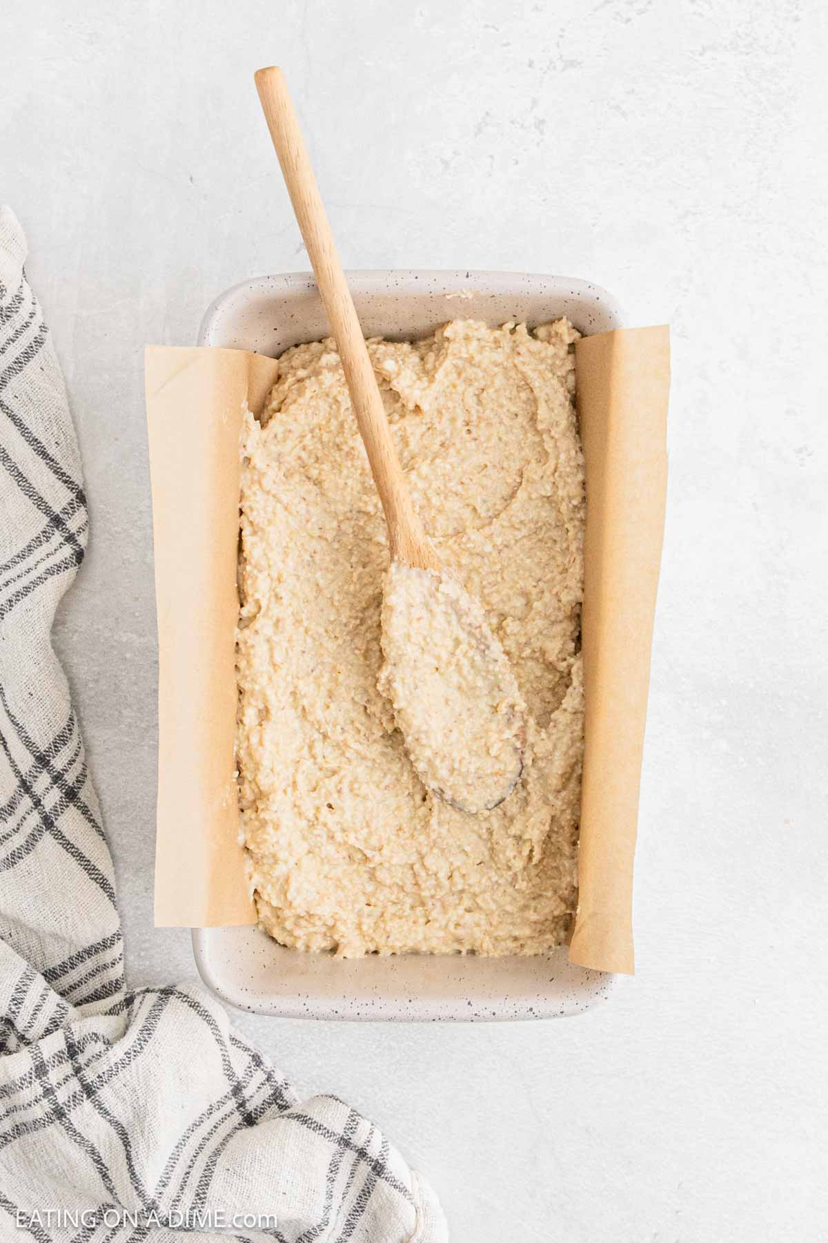 Spreading the cottage cheese bread batter into the loaf pan that is lined with parchment paper