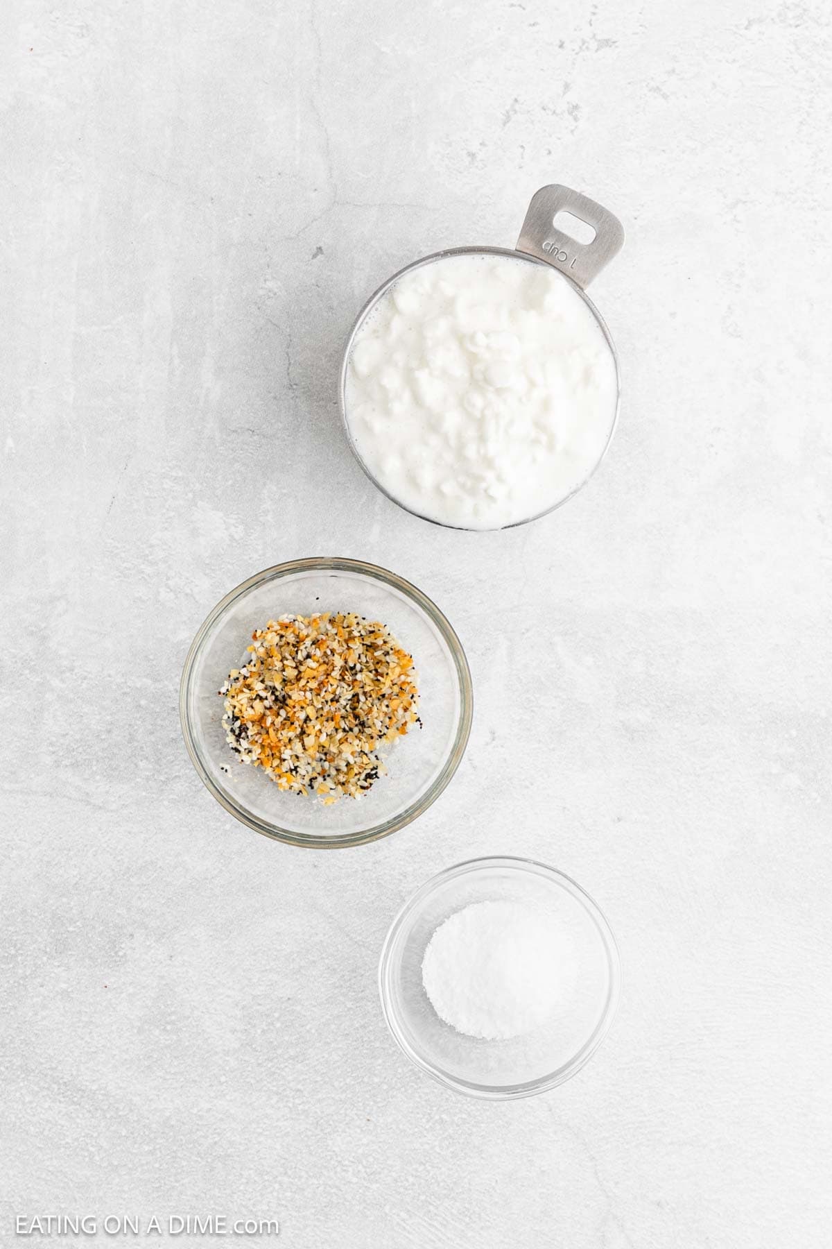 Three bowls on a light surface: one with creamy Cottage Cheese, one with everything bagel seasoning, and one with salt—perfect for making tasty Cottage Cheese Chips.