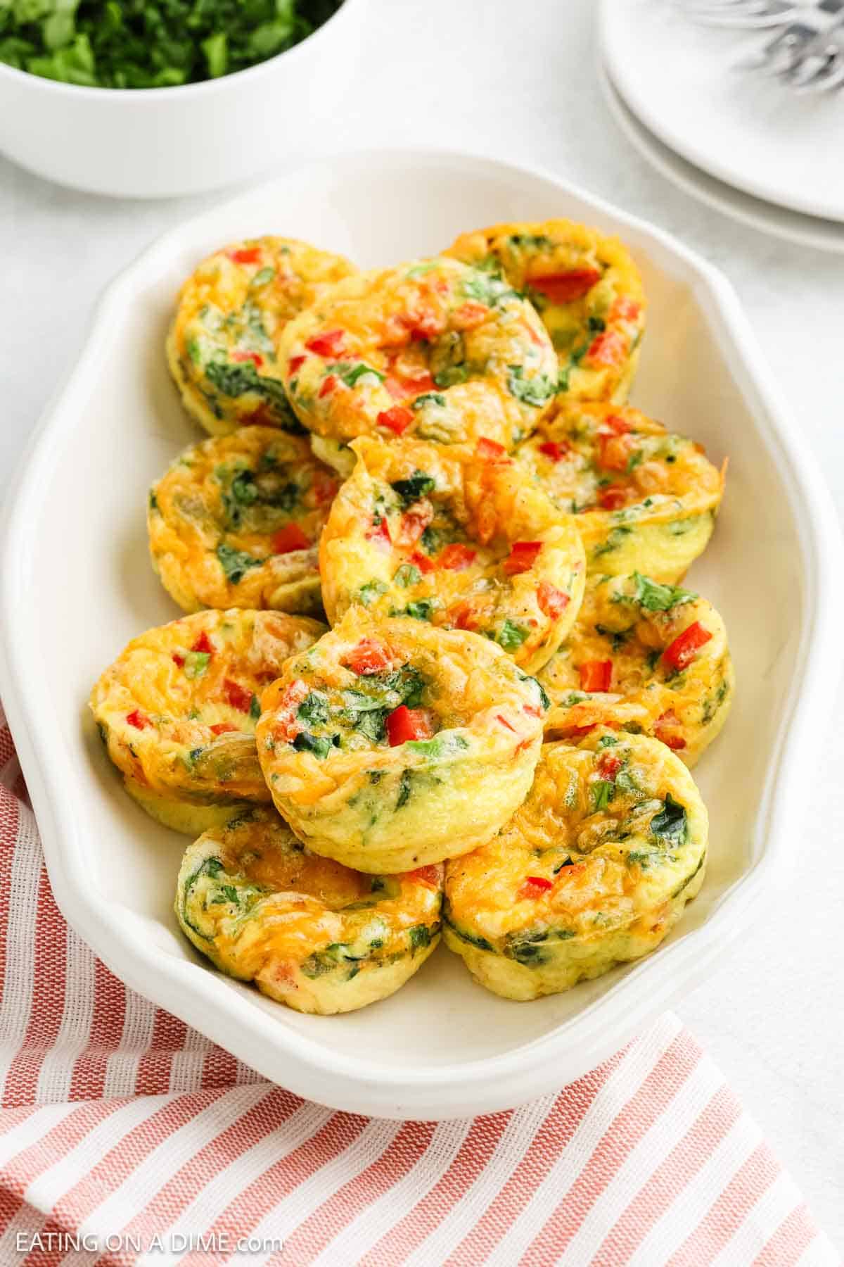 Egg Bites mixed with spinach and tomatoes on a white platter