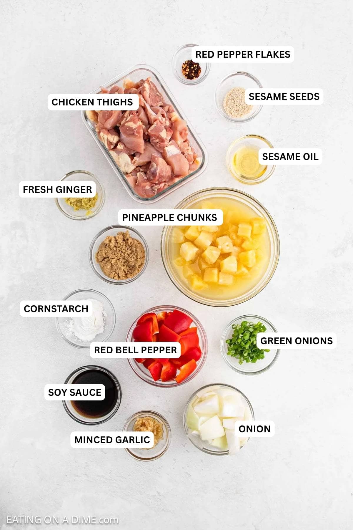 Ingredients for recipe: red pepper flakes, sesame seeds, chicken thighs, sesame oil, fresh ginger, pineapple, cornstarch, bell pepper, green onion, soy sauce, onion and minced garlic.