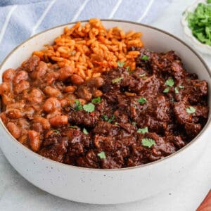 A bowl of mexican beef stew with beans and rice. Easy chile colorado recipe.