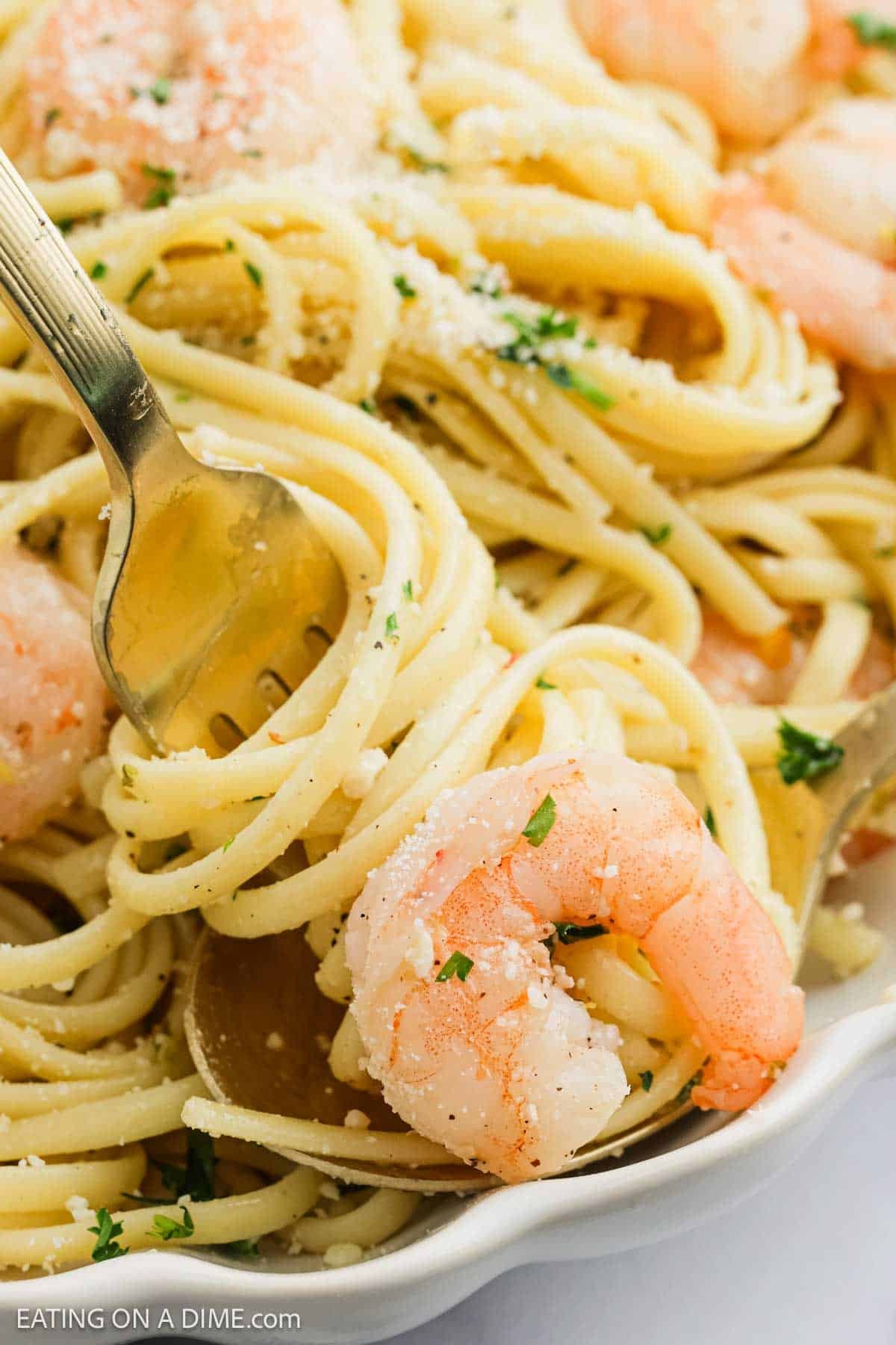 A close-up of Lemon Garlic Shrimp Pasta with linguine, garnished with chopped parsley and grated Parmesan cheese, with a fork twirling the noodles.