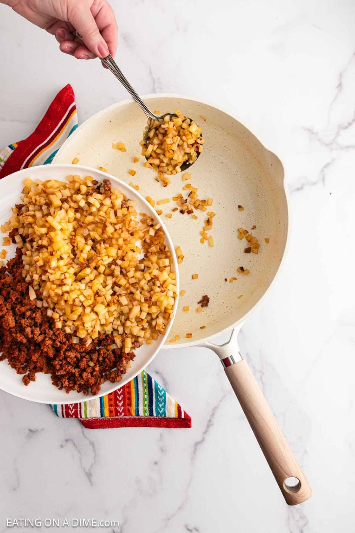 Removing the cooked diced onions and potatoes from the skillet