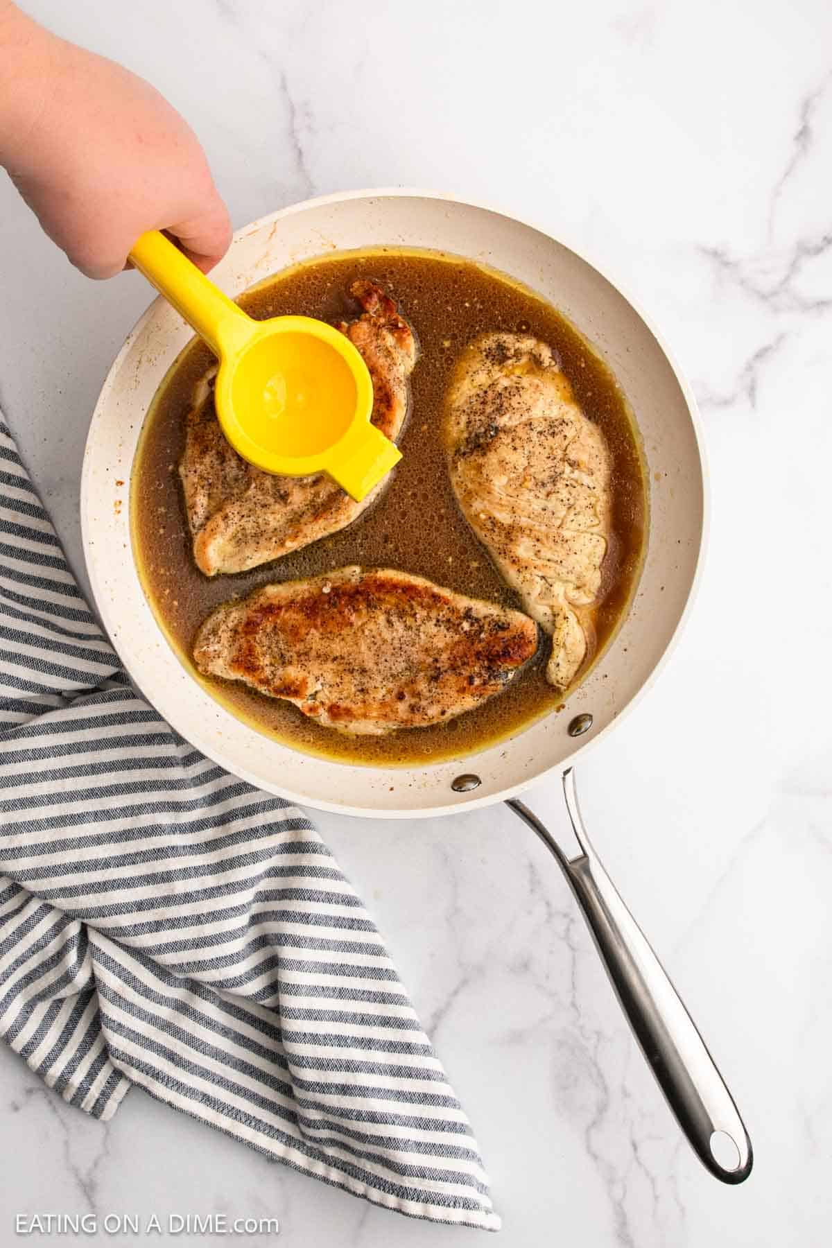 Squeezing fresh lemon juice over the chicken in the broth