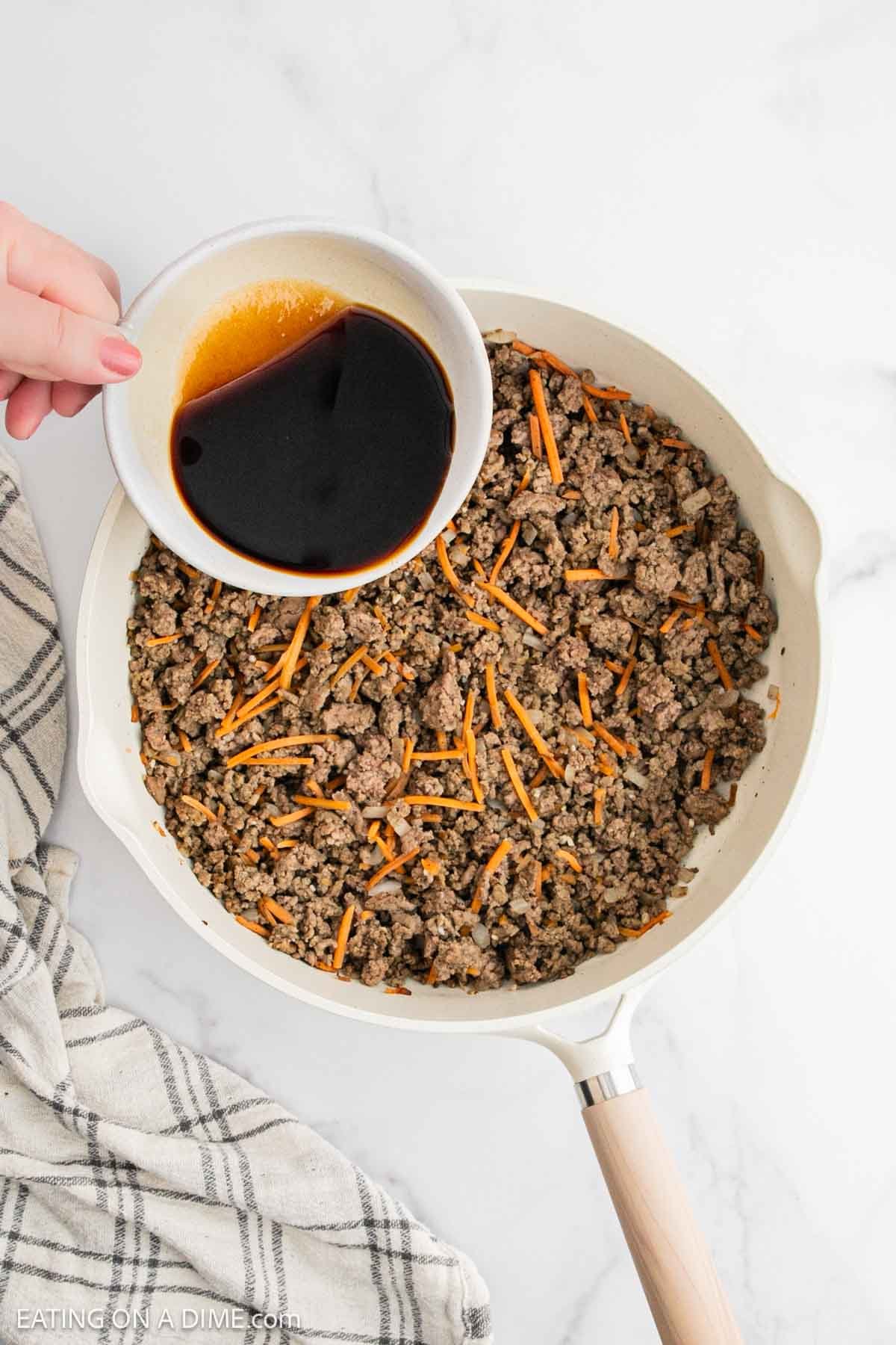Pouring the soy sauce mixture in the skillet with the ground beef mixture