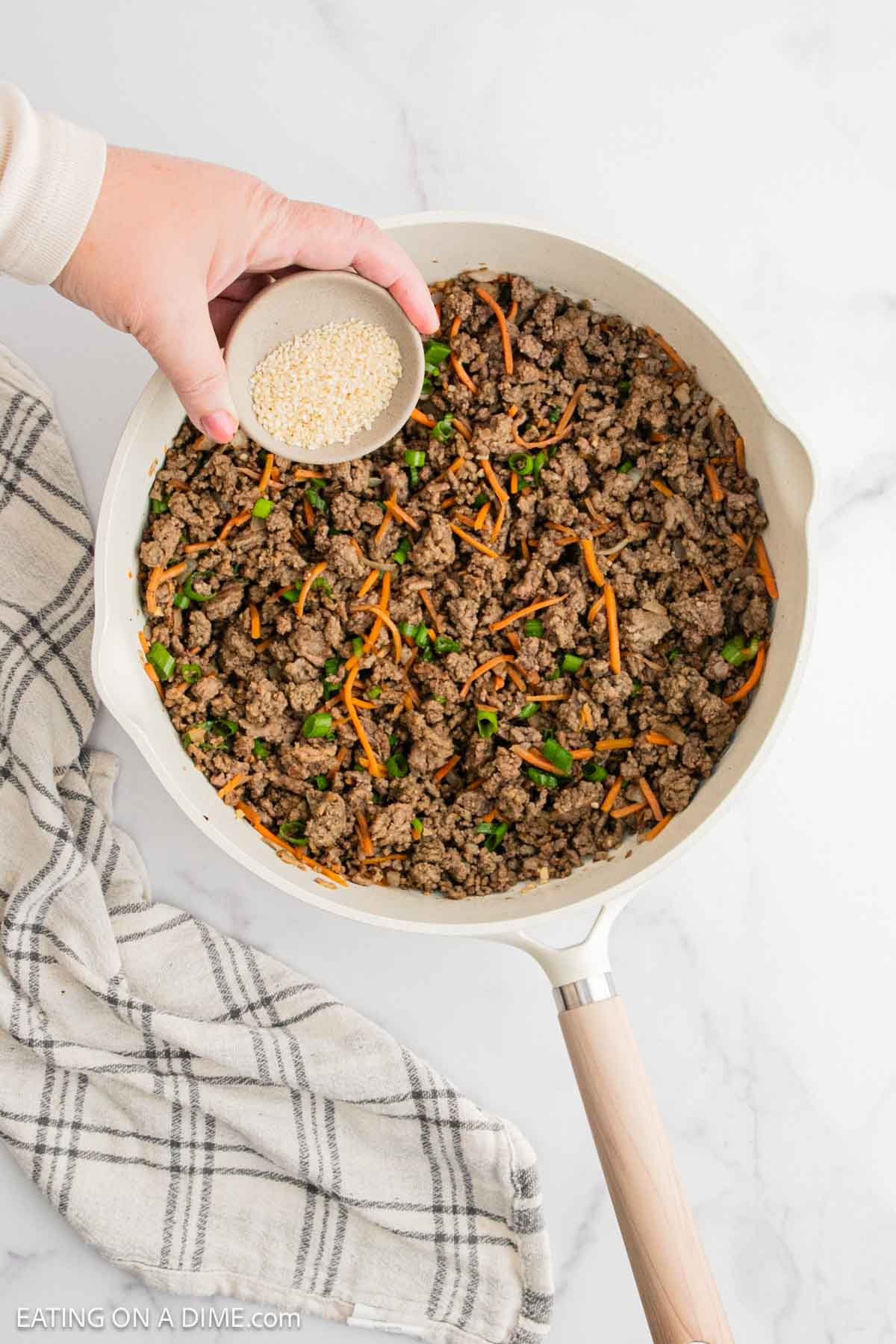Topping the ground beef mixture with sesame seeds