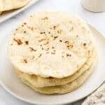 Three flatbreads stacked on a white plate.