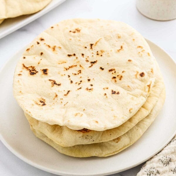 Three flatbreads stacked on a white plate.