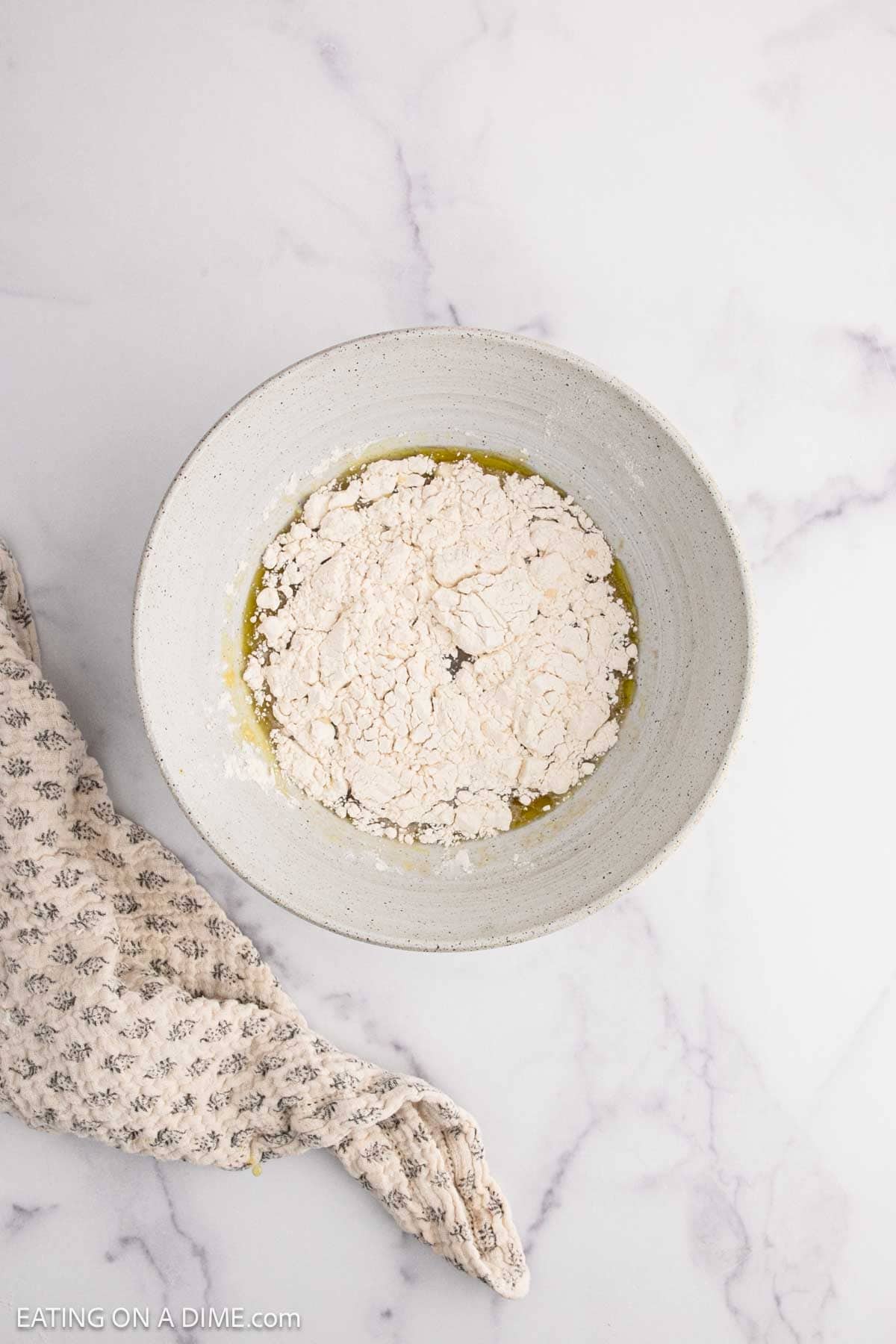 Topping the yeast mixture with flour in a bowl