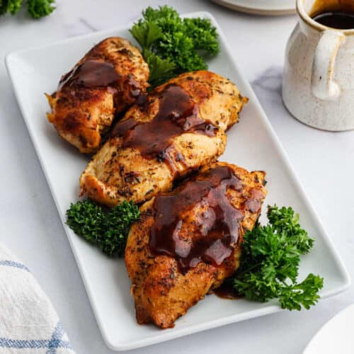 Baked bbq chicken thighs on a white plate.