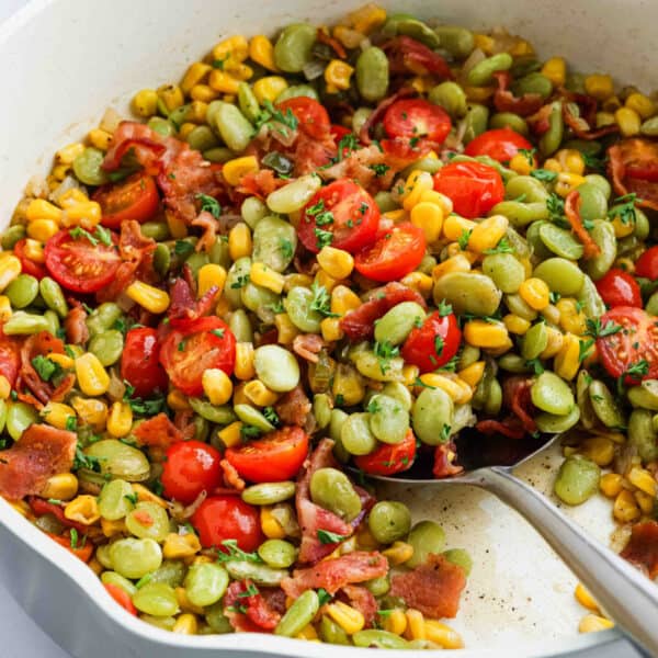 A white dish filled with corn, tomatoes and bacon.