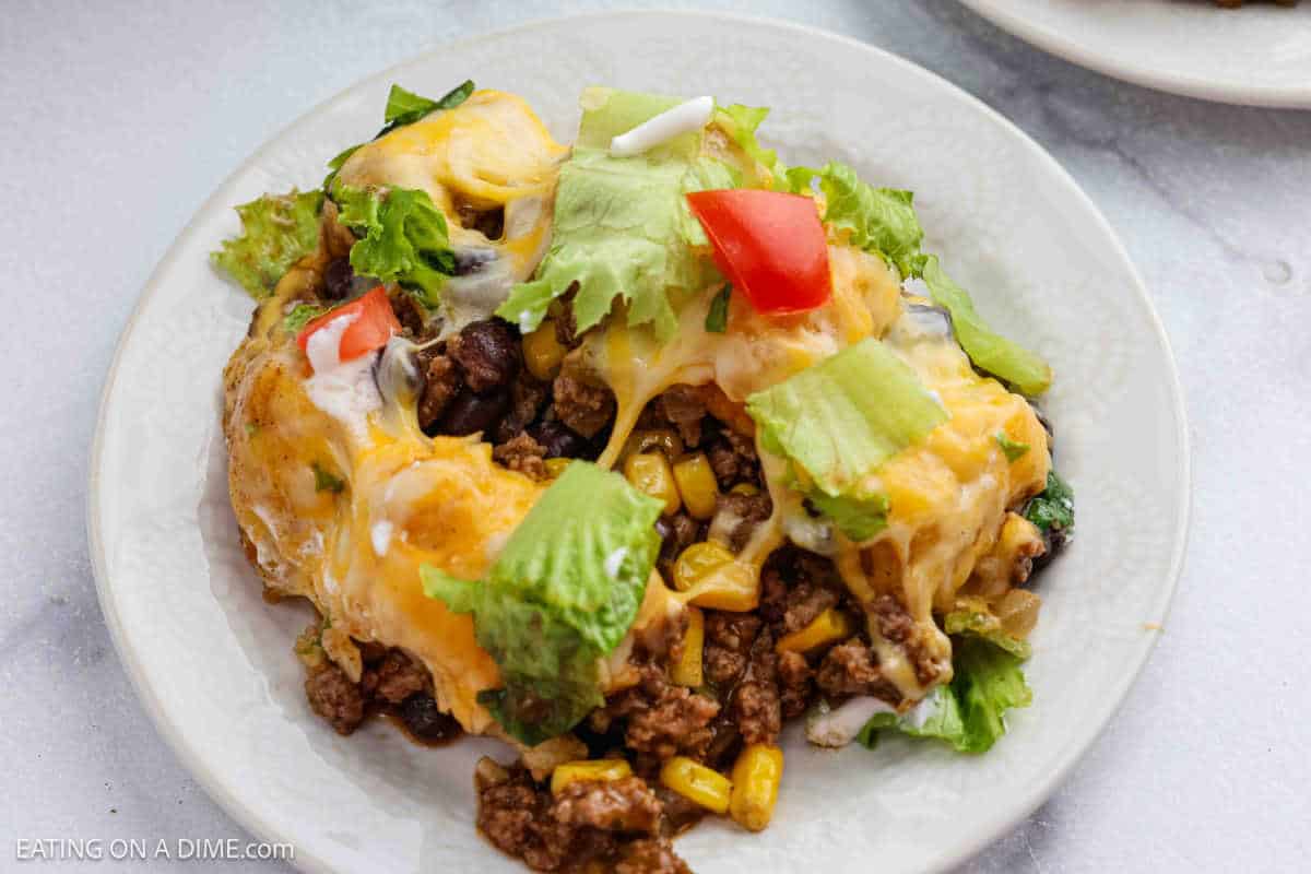 Serving of Mexican Tator Tot Casserole on a plate topped with lettuce and tomatoes.