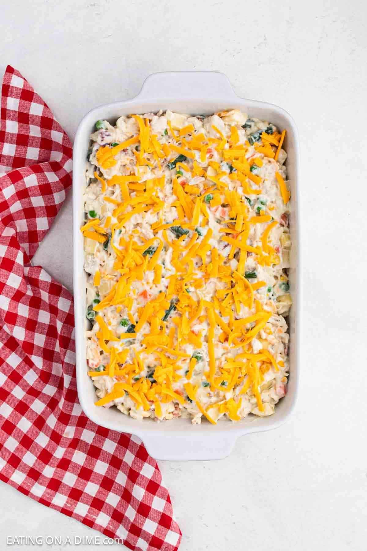 Casserole mixture in a baking dish topped with shredded cheese.