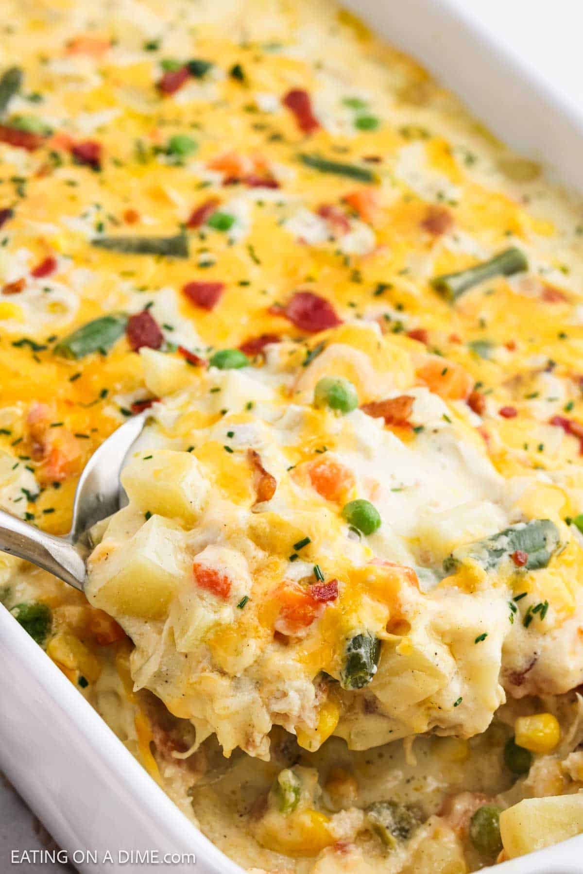 Baked casserole in a white baking dish with a serving on a silver spatula ready to be serve.