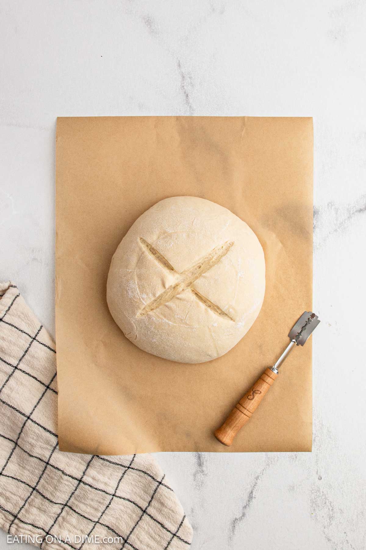 A loaf of sourdough bread rests on a paper, showcasing the results of a classic sourdough bread recipe.